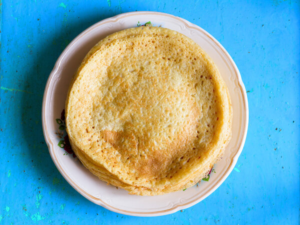 Pancake made from wheat flour in an old ceramic bowl on a blue background. Rustic style. Top view closeup. Traditional Russian dish on Shrove Tuesday Stock Image