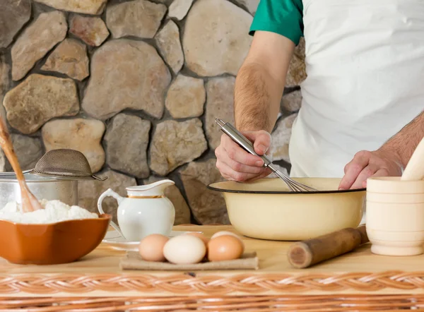 Weißes Weizenmehl, rohe Hühnereier und ein Mann kochen den Teig auf dem Steinmauern-Hintergrund. Konzept der rustikalen Küche, selektiver Fokus. Kopierraum. Freiraum für Text — Stockfoto