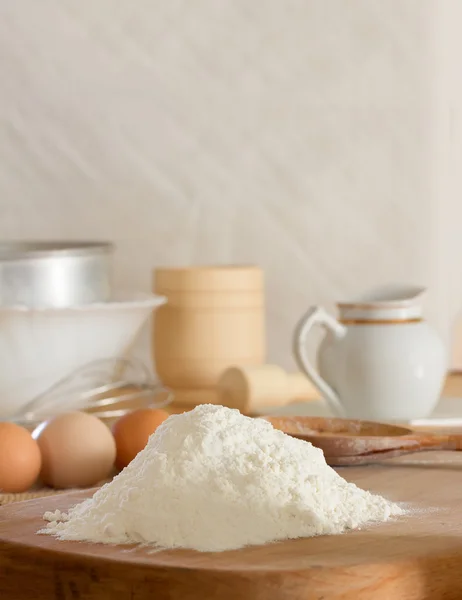 White wheat flour and raw chicken eggs to prepare the dough and kitchen utensils against a white wall. Concept of rustic kitchen, selective focus. Copy space. Free space for text — Fotografie, imagine de stoc