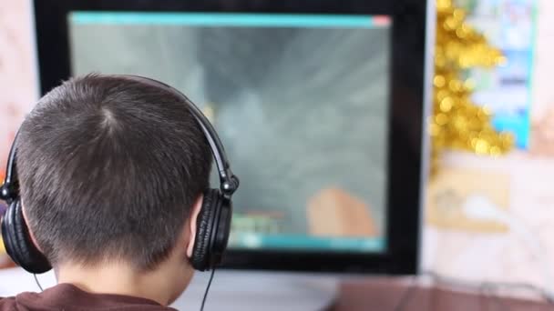 Menino branco europeu em fones de ouvido jogando o jogo de computador minecraft. o conceito de vício em jogos de azar, vício em computadores. foco seletivo — Vídeo de Stock