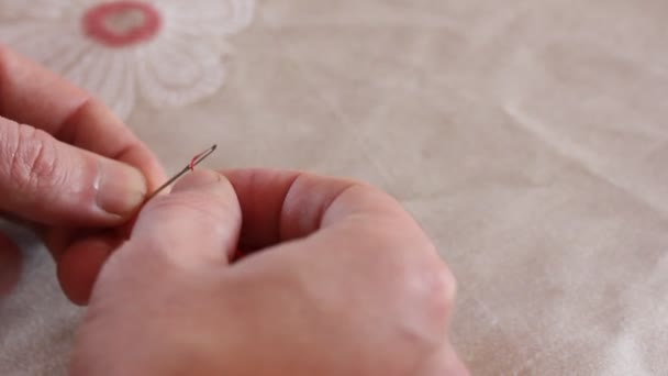 les mains des hommes blancs fils rouges l'aiguille sur le fond de tissu de lin. le concept de broderie et de couture. Espace de copie. Espace libre pour texte, mise au point sélective 