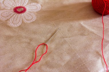 iş parçacığı arka plan desen ile keten kumaş üzerinde bir iğne ve kırmızı yumağı içinde geçirilir. Uzay kopyalayın. Boş alan için metin, yakın çekim, üstten görünüm