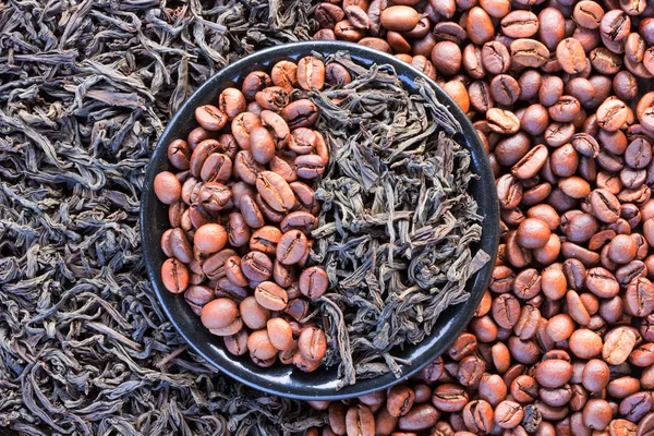 Granos de café y hojas de té negro en un platillo redondo — Foto de Stock