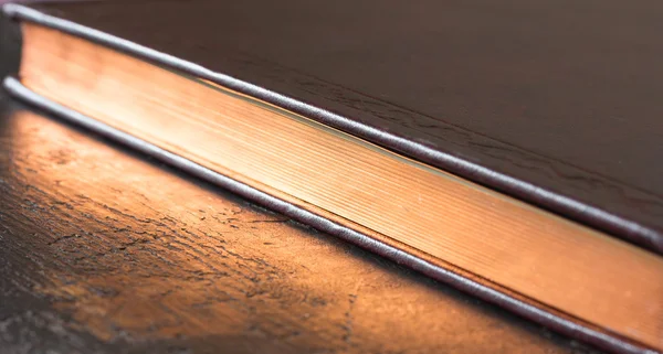 Kapalı bir kitap ile altın rengi kenarları boyunca çapraz. sığ derinlik-in tarla — Stok fotoğraf