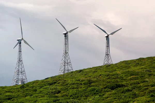 Turbin wiatrowych na zielonym wzgórzu w błękitne niebo — Zdjęcie stockowe