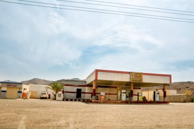 Al Ula, Suudi Arabistan - 25 Nisan 2025: Suudi Arabistan otoyolları boyunca çöl çevresi ve arka planda açık gökyüzü bulunan benzin istasyonu