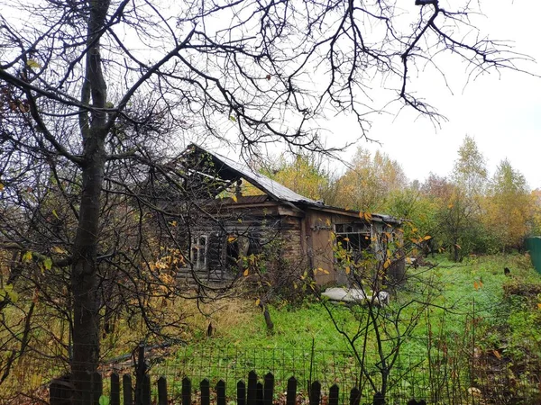 Verwüstung. das ausgebrannte Haus auf einem verlassenen Grundstück. Verwachsener Garten — Stockfoto