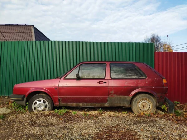 Oude kapotte auto. verlaten roestige auto bij het hek in de tuin — Stockfoto