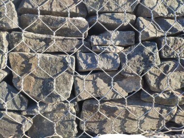 Gabiyondan yapılmış çitler, kaya çitleri. Gabion çitinin dokusu doğal taş ve metal ağdan yapılmıştır.