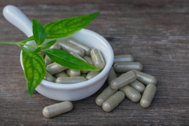 Andrographis 'in tahta arka planda paniklediği kapsüller, Andrographis' in paniklediği bitki virüs hücrelerinin bölünmesini engelliyor..