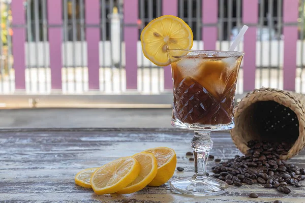 Ice black coffee lemon, and sliced lemon on old wooden background.