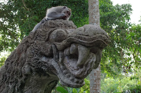 Yengeç yiyen makak ejderha heykeli üzerinde — Stok fotoğraf