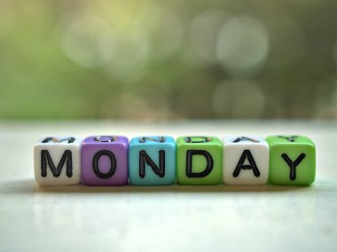 Pazartesi alfabesi alfabe renkli kelime beyaz masa üzerinde bokeh bulanık yeşil bahçe arka planı, yaratıcı kart tasarımı için mutlu sabah, taze sabah günü