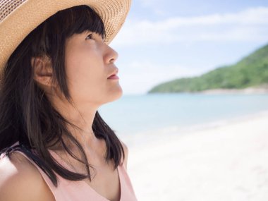 Yalnız bir portre, ne yazık ki bulanık bir dağ ve mavi deniz görüntüsü üzerinde duran bir kadın. Siyah saç ve ten rengi otantik Tayland. Yaz tatili ya da kırık kalp konsepti.