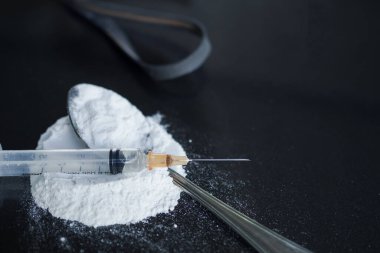 Şırıngada morfin, kaşıkta morfin ve siyah tahta arka planda siyah kauçuk bant. Yasadışı uyuşturucu. Bağımlılık yapıcı madde, uyuşturucu, alışkanlık yapıcı madde kavramı.