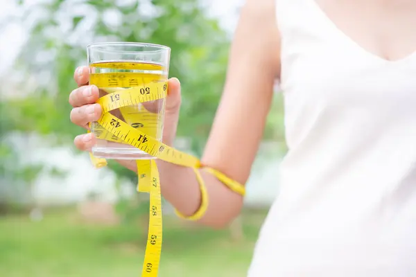 手握水杯的妇女带着带尺寸的模糊背景 体形女孩和喝酒减肥的概念 — 图库照片