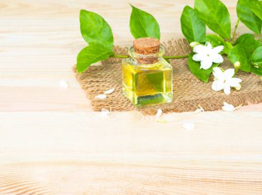 Ahşap arka planda cam şişede yasemin yağı. Spa ve aromaterapi kavramı.