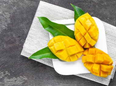 Beyaz tabakta dilimlenmiş, ahşap kaplama sarı mango. Sağlıklı yaşam için tropikal meyve ve yiyecek.