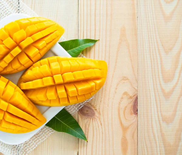 Beyaz tabakta dilimlenmiş, ahşap kaplama sarı mango. Sağlıklı yaşam için tropikal meyve ve yiyecek.