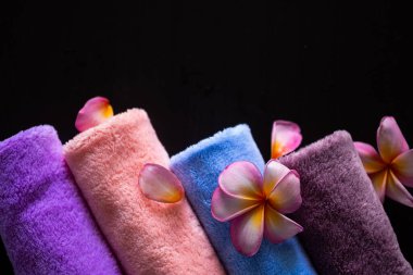 Siyah arka planda Plumeria çiçekleri olan bir spa havlusu. Lüks tuvalet oteli için. aromaterapi ve spa konsepti.