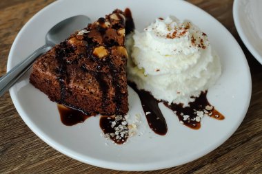 Bademli çikolatalı pasta ve beyaz tabakta krem şanti. atıştırmalık veya tatlı yiyecek konsepti.