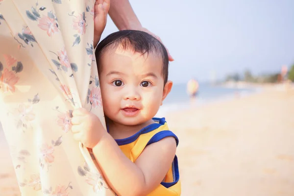 Littel boy 1 year old hugging mom with excitement and joy on blue sea blur image. mom and child in travel summer holiday concept.