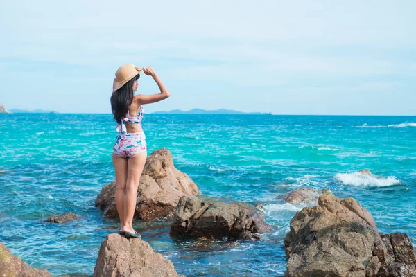 Asia women standing in sea with hat and swimming suit of outdoor summer holiday on blur image blue sea background.