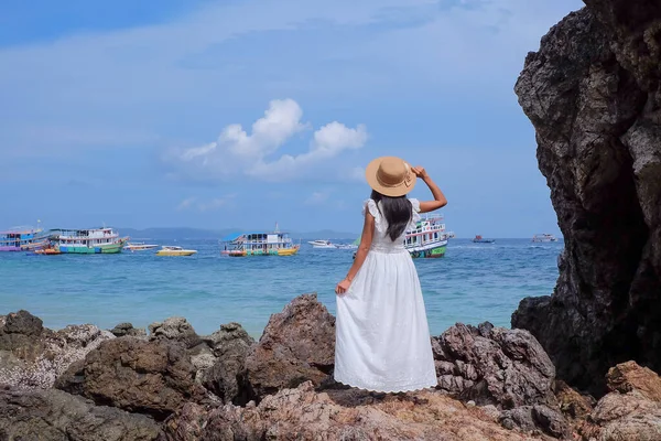 Asian women standing on stone with white dress she happy of outdoor summer on sand beach with blue sky and sea, well editing text present for your project with tourism and travel on summer season.