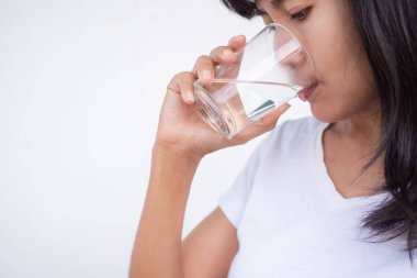 Asyalı kadın beyaz arka planda su içiyor. Sağlığın için saf su iç. Bayan otantik ten teni.