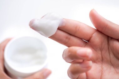 Beyaz arka planda bir kavanozda losyon görüntüsü olan parmaklardaki nemlendirici kremi kapat. Kozmetik alerji testi için. Güzellik ve sağlık hizmeti konsepti. otantik ten teni parmaklar