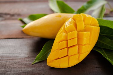 Tropikal meyveli mango. Tahtada yapraklarla dilimlenmiş mango. Atıştırmalık, kahvaltı tatlı yemek ve sağlık için yaz meyveleri..