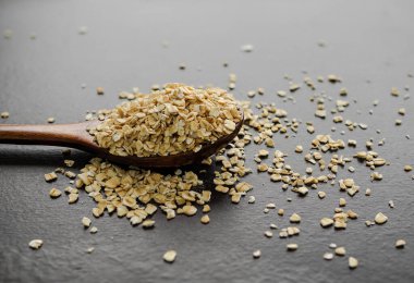 Yulaf ezmesi ya da ahşap kaplamalı kaşık üzerinde yuvarlanmış yulaf ezmesi. Sabah konseptinde sağlıklı beslenme ve beslenme için organik doğa atıştırmalıkları.