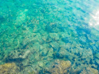 Dalgalar altında mavi deniz altında taş dokusu, yukarıdan bakıldığında yaz tatili veya okyanus kıyısı doğası hakkında bir makale oluşturmak için kullanılıyor..