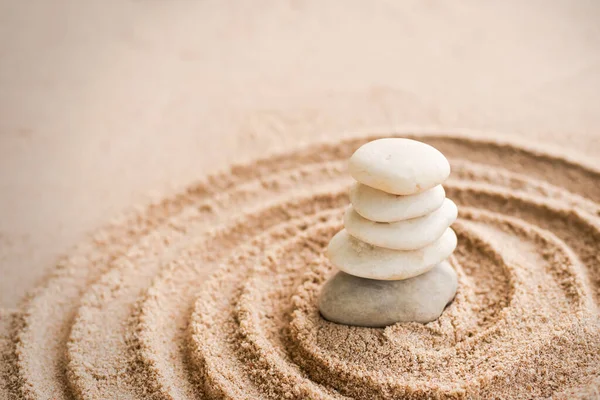 Japanese zen garden stone on sand beach. rock or pebbles with plumeria flowers with copy space. for aroma therapy spa on summer holidays. meditation wellness and tranquility Japanese concept.