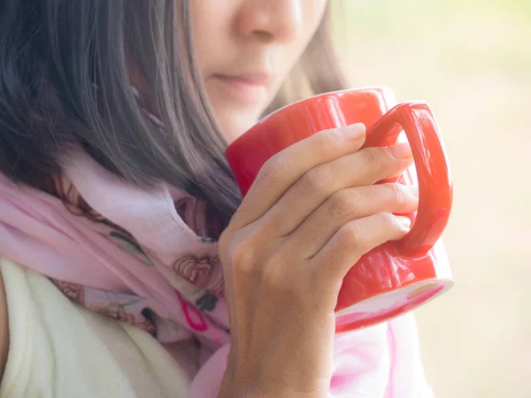 Close up woman holding a red coffee cup with hot coffee on blur image background. lady drinking coffee in a morning. tot drink concept.