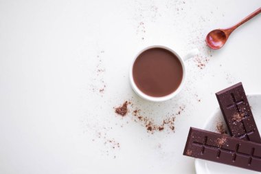 Beyaz fonda çikolatalı süt ve beyaz arka planda çikolata. Sabahları sıcak hindistan cevizi, sağlık için. Dünya Çikolata Günü ve aperatif veya kahvaltı konsepti. düz yatay kopyalama alanı.