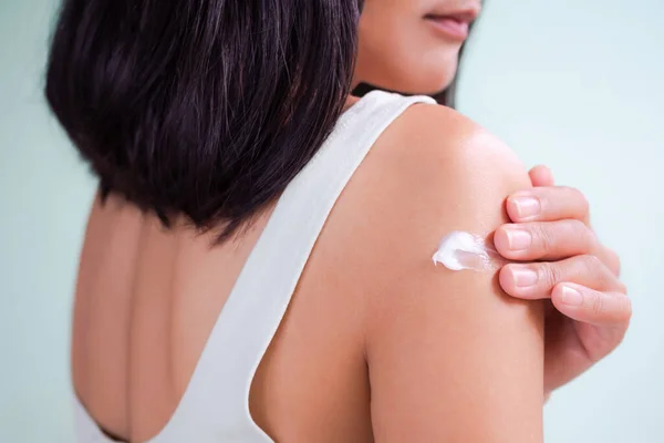 Kadın evde banyo yaptıktan sonra el kremi sürerek nemlendirici krem sürüyor. Güneş koruması, cilt bakımı, genç görünümlü cilt için. Güzellik için kozmetik. otantik siyah saç, ince formda kız ve ten rengi..