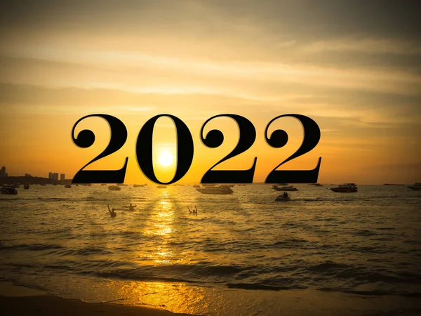 Merry Christmas and happy new year 2022 concept. text and number on twilight evening sun set with shadow text on sea ocean and sky background. for celebrate holidays and new beginning next year.