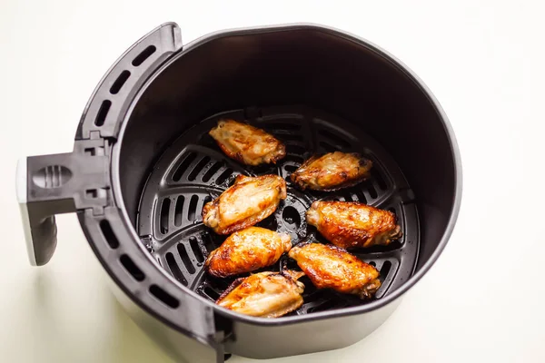 Baked chicken wings in Air Fryer on white table background. cooking for low fat control weight. food for health concept.