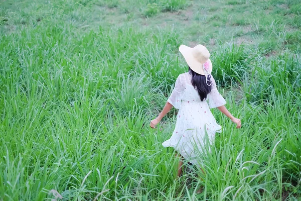 Alone woman with hat and white dress walking on green grass park. free space. tourist tropical summer nature holidays. happy lifestyle. broken heart or love valentine day  concept.