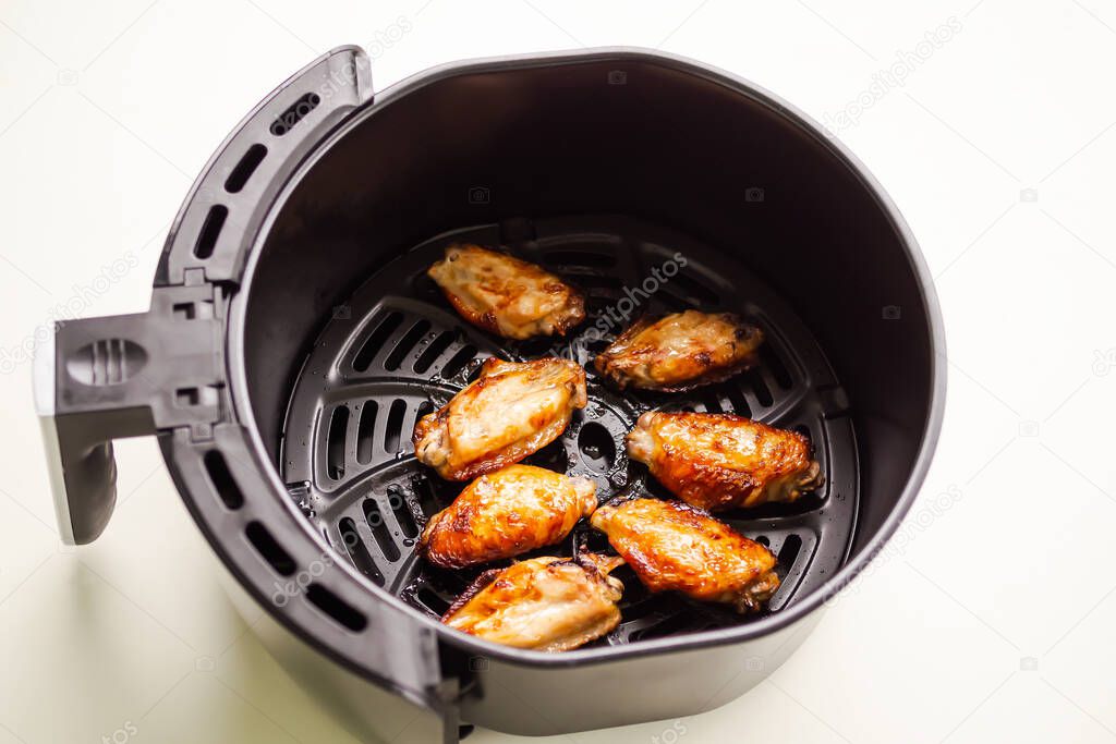 Baked chicken wings in Air Fryer on white table background. cooking for low fat control weight. food for health concept.
