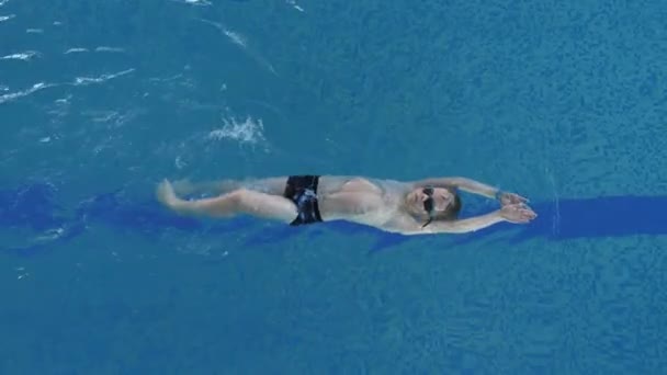 Enfant caucasien Backstroking dans la piscine. Formation à la natation et activités sportives — Video