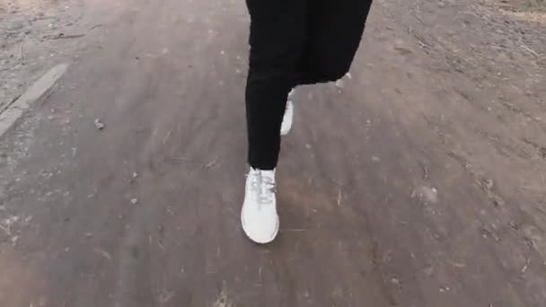 白いスニーカーの女の子は道に沿って歩くと彼女の足を上げる — ストック動画