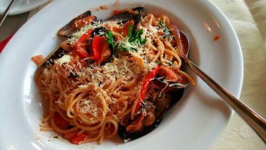 Beyaz tabakta karides ve midyeli makarna.