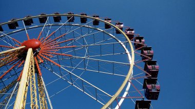 Lunaparkta mavi gökyüzüne karşı dönen dönme dolap.