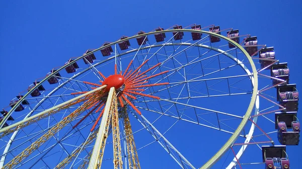 Ferris wheel with booths against the blue sky in the amusement park — Stock Photo, Image
