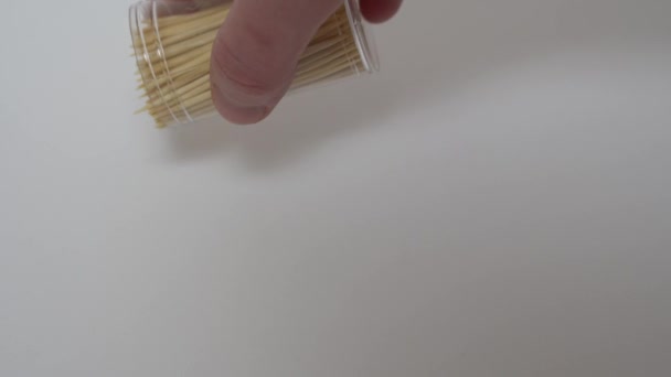 Hand häller tandpetare på en vit yta från en burk — Stockvideo
