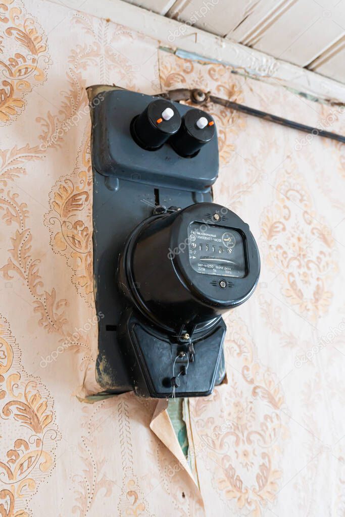 Belarus, Bakshti - January 10, 2021: Home vintage country house electricity meter hanging on the wall
