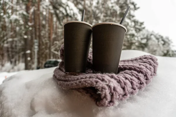 Dos tazas de papel con café mantener caliente en una bufanda en la nieve, cuento de amor de invierno —  Fotos de Stock