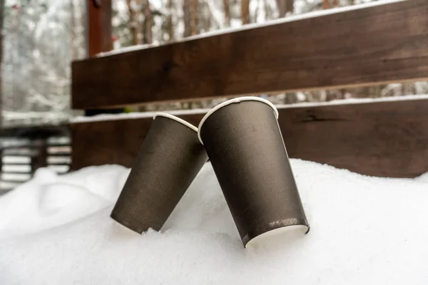 Twee papieren bekers met koffie op een sneeuwbank zoenen elkaar in de winter — Stockfoto